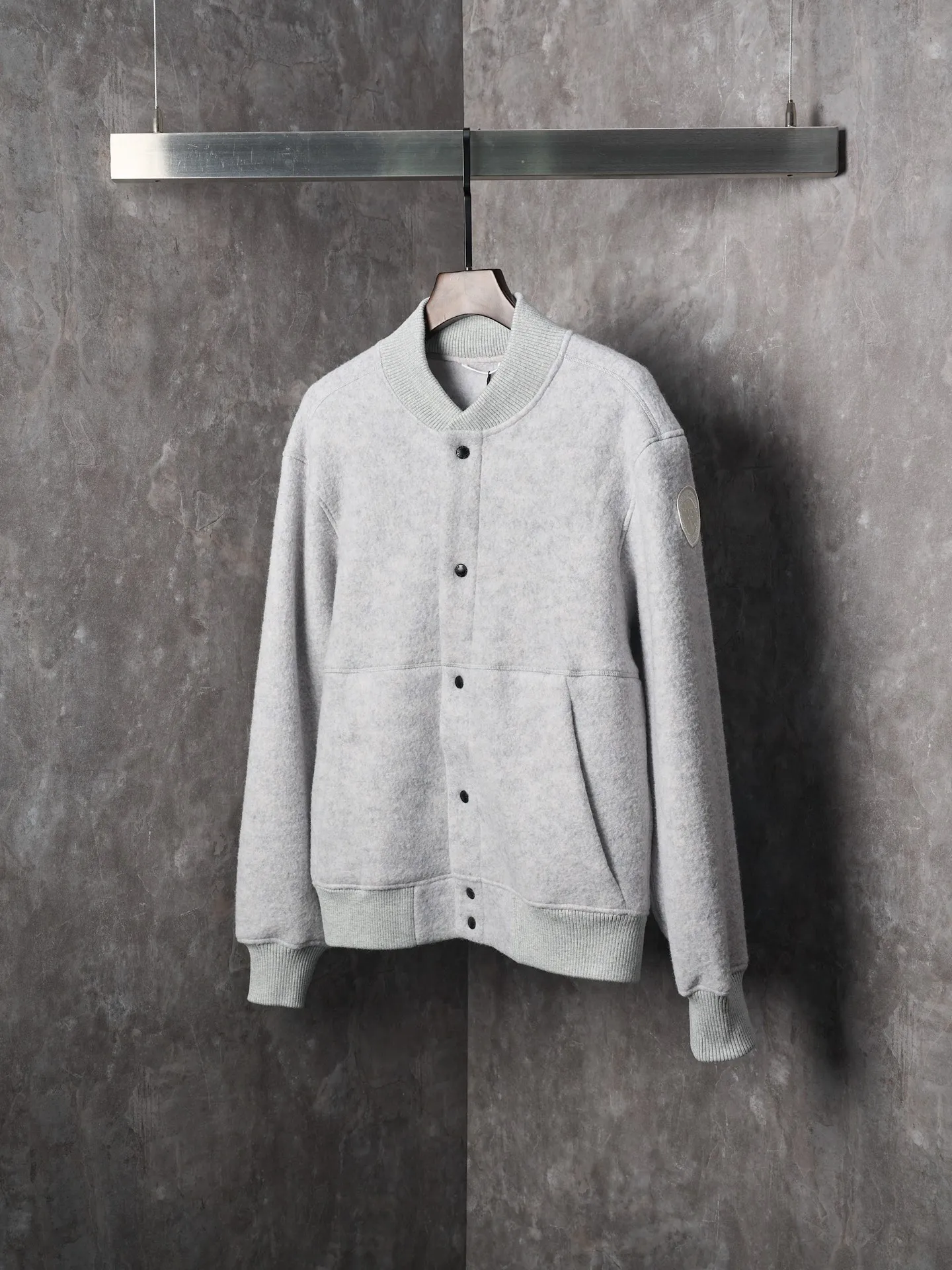 P760 Actual hanging auction] Canada Goose/Canada Goose Fleece Badge Button Cashmere Jacket [Color] Dark Gray Light Gray [Size] S M L XL Wool Blend Fabric: The main fabric of this jacket is light gray wool blend fabric to improve the wear resistance, wrinkle resistance and warmth of the fabric. Wool provides good warmth and a natural feel, while blended fibers enhance the fabric's practicality and durability.  RIBBED KNIT: The collar, cuffs and hem are ribbed knitted for added stretch and fit.  The cutting process needs to ensure that the texture and color of the fabric are evenly distributed, especially with this light gray tone, to avoid chromatic aberrations. The stretchability of wool-blend fabrics needs to be taken into consideration when cutting pieces to ensure dimensional stability of the finished garment.      Use a sewing needle and thread suitable for wool-blend fabrics to avoid damage to the fabric during sewing. The sewing stitches are even and firm to prevent thread stripping.      The temperature needs to be controlled during ironing to avoid high temperature damage to the fabric while keeping the fabric smooth and crisp.   The front and back body parts, sleeves and other main parts are stitched with flat seams to ensure a smooth silhouette.   Align the fabric texture at the splices to keep the look neat.     Details such as pockets and cuffs are designed with inset pockets to increase practicality and aesthetics.     The splicing areas are reinforced to improve durability.  The white circular armband on the left arm is an important part of the brand identity and is finely sewn to ensure it is strong and flat.